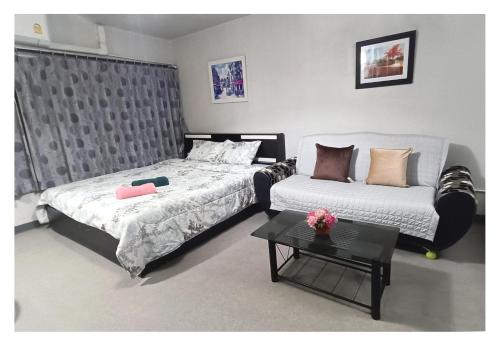 a bedroom with a bed and a couch and a table at Impact Arena C3 Milo in Nonthaburi