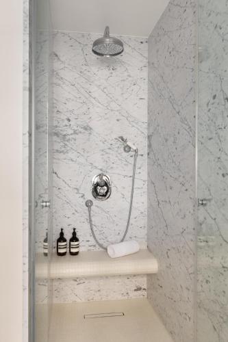 La salle de bains est pourvue d'une douche et de murs en marbre blanc. dans l'établissement HIGHSTAY - Luxury Serviced Apartments - Victoires, à Paris