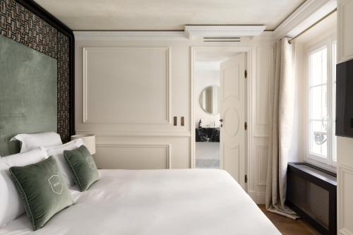 - une chambre avec un lit blanc et des oreillers verts dans l'établissement HIGHSTAY - Luxury Serviced Apartments - Victoires, à Paris