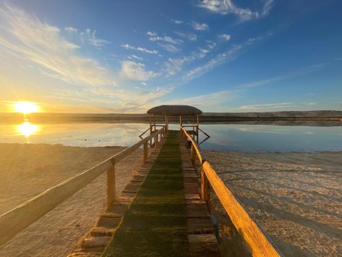 a pier on the beach with the sun in the background at Ahmed Safari Camp in Bawiti