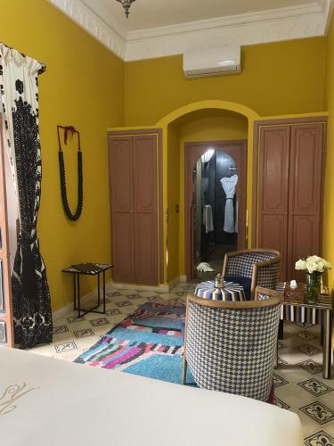 a living room with yellow walls and a table and chairs at Riad Ksar Al Amal & Spa in Marrakech