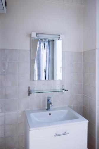 une salle de bain blanche avec un lavabo et un miroir dans l'établissement Occigite, à Valence