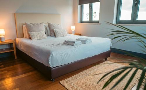 a bedroom with a large white bed with pillows at Villa Caparica Hostel in Costa da Caparica