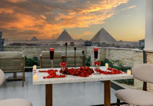 a table with red flowers on it with the pyramids at Rixoss Tower Pyramids View in Cairo