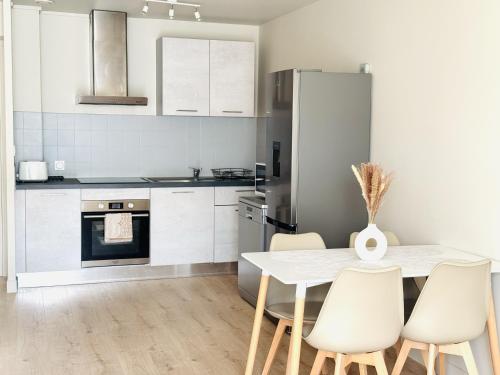 - une cuisine avec une table et des chaises blanches dans l'établissement Le Dolcevita Magnifique T2 à 10min de la gare à pieds, à Bellegarde-sur-Valserine