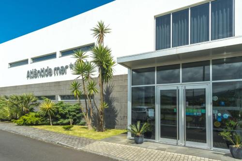 an office building with palm trees in front of it at Atlantida Mar Hotel in Praia da Vitória