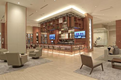 a lobby with chairs and a television in a building at AC Hotel by Marriott Fort Lauderdale Airport in Dania Beach