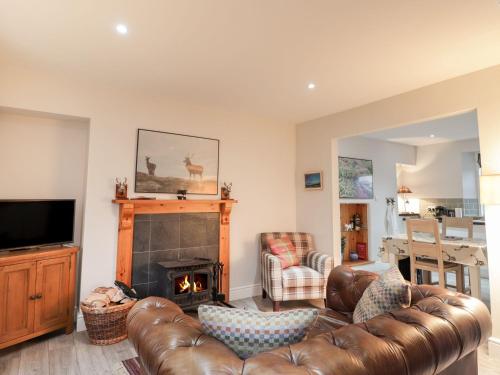 a living room with a leather couch and a fireplace at Wendy's Place in Inverness