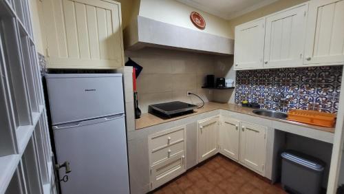 a small kitchen with white cabinets and a white refrigerator at The Blue Hydrangea in Vila Franca do Campo