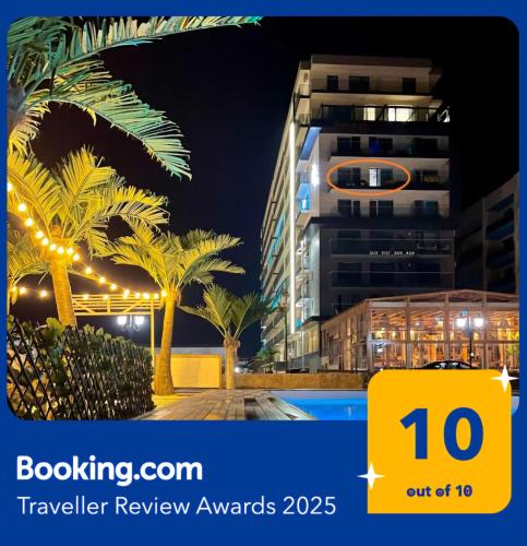 a view of a building with palm trees and lights at Promenada Sea View with private parking in Mamaia Sat/Năvodari