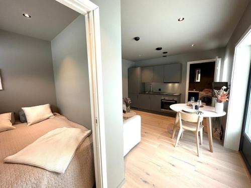 a bedroom with a bed and a table and a kitchen at New apartment in quiet area close to Oslo in Asker