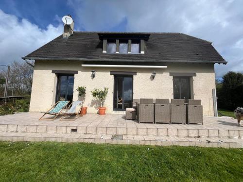 une maison dotée d'une terrasse avec deux chaises devant elle dans l'établissement Maison entre mer et campagne, à Douville-en-Auge