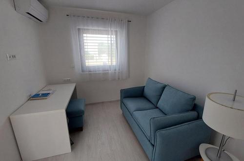 a small living room with a blue couch and a desk at PERISKA Home in Kaštela