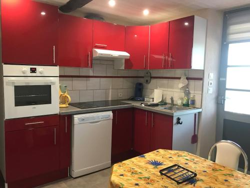 eine Küche mit roten Schränken und einem Tisch darin in der Unterkunft Le NORD AU SUD pour 2 personnes in Villecroze