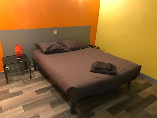 Ce lit se trouve dans une chambre dotée d'un mur orange. dans l'établissement Le NORD AU SUD pour 2 personnes, à Villecroze