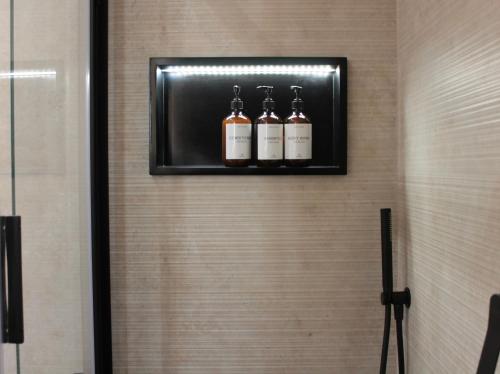 a shelf with three bottles of alcohol on a wall at Home Sweet Rome Lucina in Rome