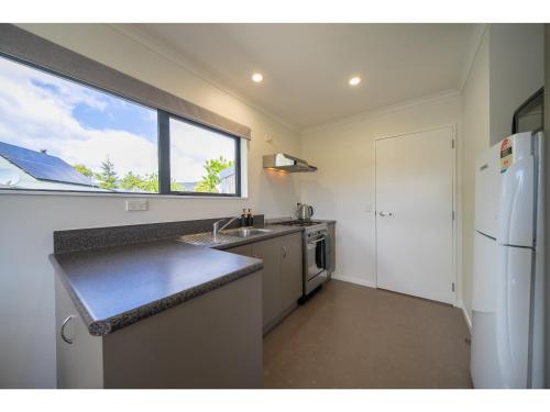 a kitchen with a sink and a refrigerator and a window at Cosy Lakeside - Manapouri Holiday Home in Manapouri