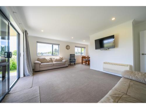 a living room with a couch and a flat screen tv at Cosy Lakeside - Manapouri Holiday Home in Manapouri