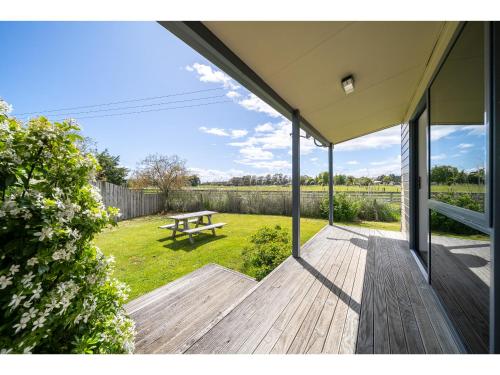 a wooden deck with a picnic table in the yard at Cosy Lakeside - Manapouri Holiday Home in Manapouri