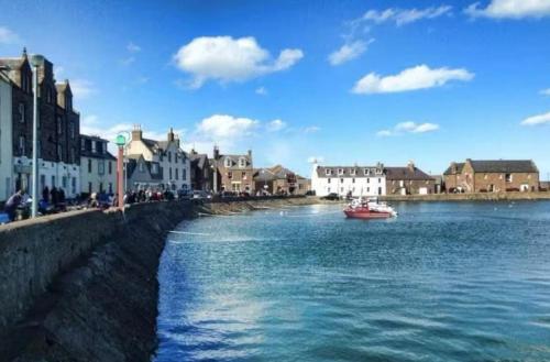 a boat in a body of water next to buildings at Stonehaven Centre - Fetteresso Apartment in Stonehaven