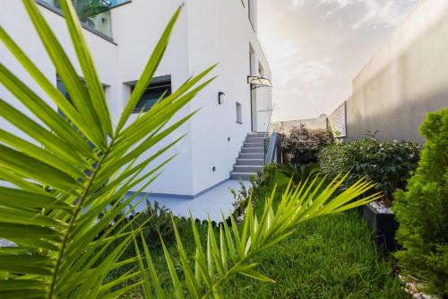 a white house with green plants in the yard at VILLA HELENA Amber Apartment in Caniço
