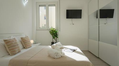 ein weißes Schlafzimmer mit einem Bett mit Handtüchern darauf in der Unterkunft Hampsicora Apartment in Alghero