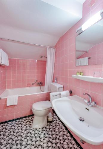a pink bathroom with a tub and a toilet and a sink at Berghaus - Der Westerhof Hotel in Tegernsee