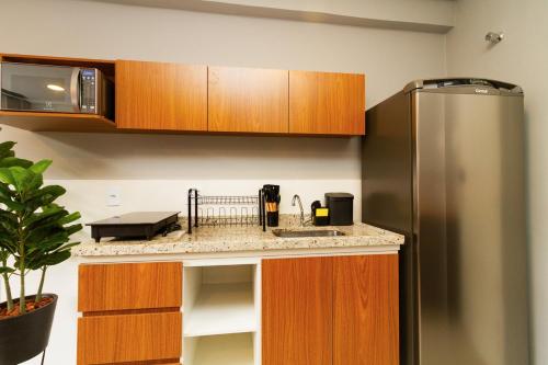 a kitchen with a stainless steel refrigerator and wooden cabinets at 360 Sanfran Riachuelo in Sao Paulo