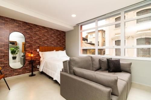 a bedroom with a bed and a couch and a window at 360 Sanfran Riachuelo in Sao Paulo