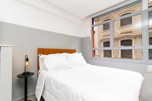 a white bedroom with a bed and a window at 360 Sanfran Riachuelo in Sao Paulo