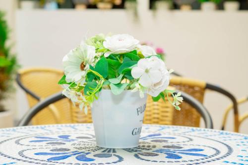 a white vase with white flowers on a table at Hotel Galería La Vieja Sara in Ríohacha