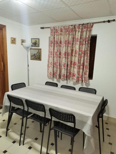 a dining room table with chairs and a curtain at Casica de Hellín in Hellín