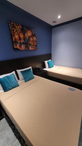 two beds in a room with blue walls at Hotel Del Centro in Guayaquil