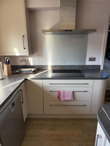 a kitchen with white cabinets and a stove top oven at The Stables East Lodge Country House in Great Rowsley