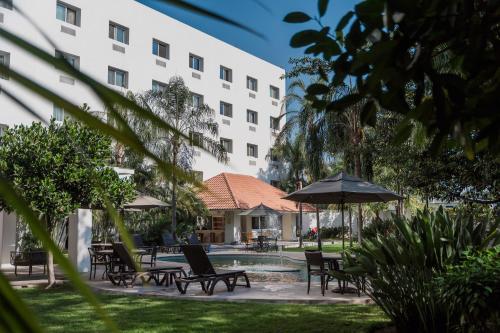a group of chairs and an umbrella next to a building at Comfort Inn Puerto Vallarta Golfside & Marina in Puerto Vallarta