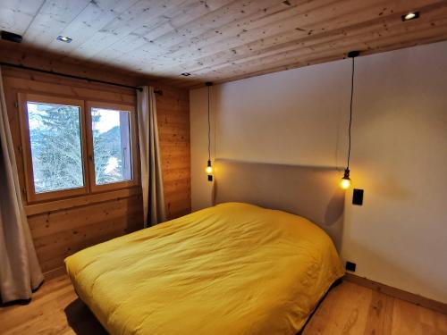 une chambre avec un lit jaune et une fenêtre dans l'établissement Appartement-Plateau d'Assy, à Passy
