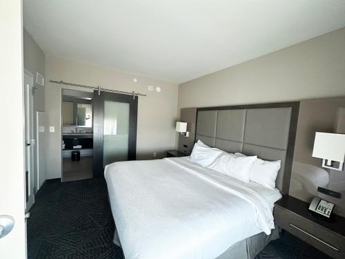 a hotel room with a large bed and a bathroom at Embassy Suites by Hilton Kansas City Olathe in Olathe