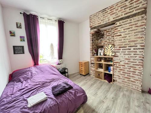 - une chambre avec un lit violet et un mur en briques dans l'établissement Appartement avec terrasse a 10min a pied du centre et de la gare, à Troyes
