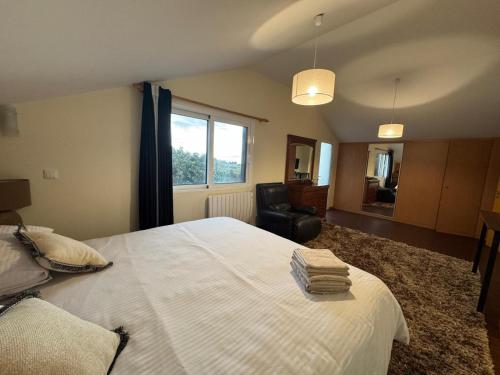 a bedroom with a bed and a chair and a window at Prazeres Natura in Prazeres