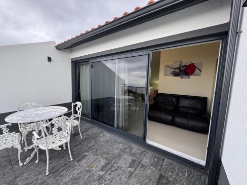 a balcony with a table and chairs and a couch at Prazeres Natura in Prazeres