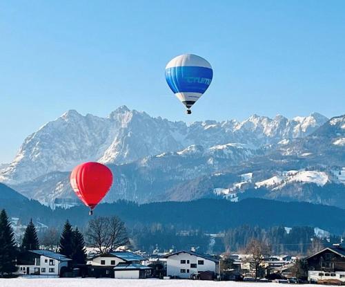 two hot air balloons flying over a snowy mountain at Ferienhaus Hetzenauer in Kössen