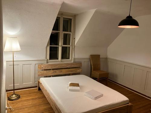ブルクドルフにあるOld Charming Rustic Swiss Mansarde 60m2 Center Burgdorf Parking Small Bathのベッドルーム(ベッド1台、ランプ、椅子付)