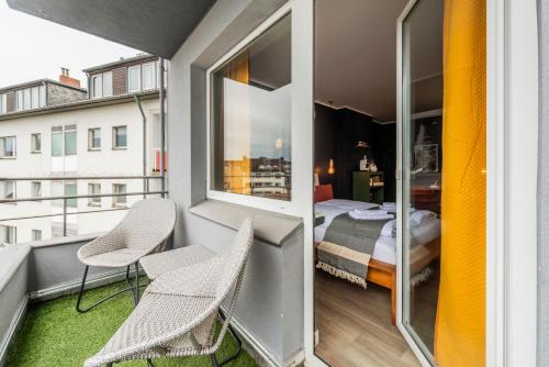 a small balcony with two chairs and a bed at Klassen Stay - Design Apartments direkt am HBF Aachen in Aachen