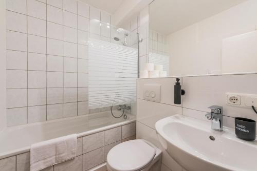 a white bathroom with a toilet and a sink at Klassen Stay - Design Apartments direkt am HBF Aachen in Aachen