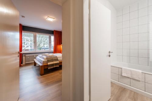 a bedroom with a bed and a bathroom with a tub at Klassen Stay - Design Apartments direkt am HBF Aachen in Aachen