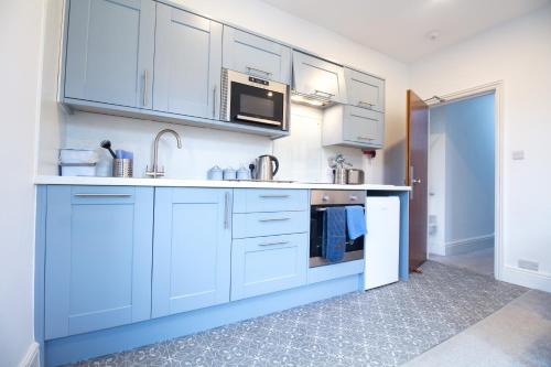a kitchen with white cabinets and a sink at Allerdale in Torquay