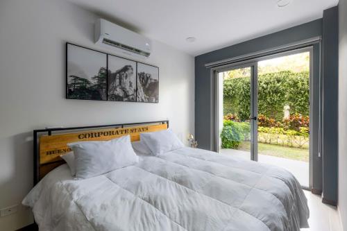 ein Schlafzimmer mit einem weißen Bett und einem großen Fenster in der Unterkunft Urban Flats Studios by Corporate Stays in San José