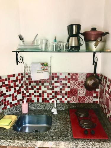 a kitchen counter with a sink and some pots and pans at Amarelo Hibisco in Guarda do Embaú