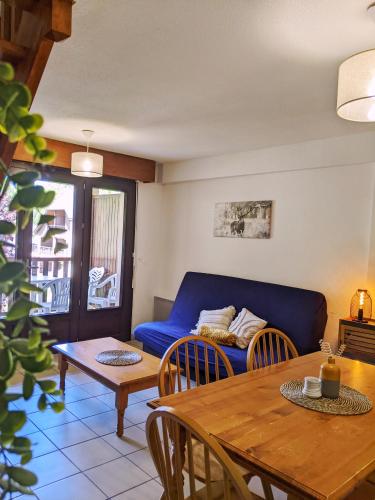 a living room with a blue couch and a table at Appt T3 calme bord du lac avec piscine in Loudenvielle