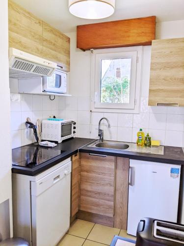 a small kitchen with a sink and a microwave at Appt T3 calme bord du lac avec piscine in Loudenvielle
